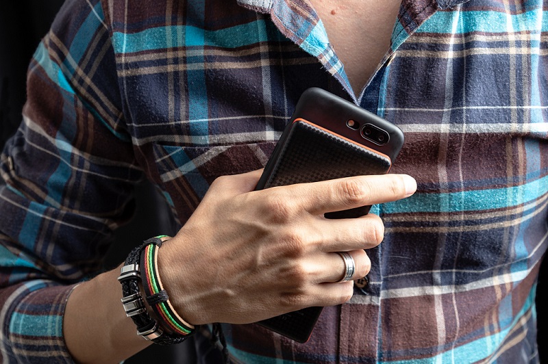 homme portant une chemise à carreaux et un téléphone dans la main