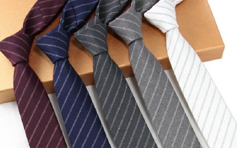 Five plain and striped cotton ties on a white background