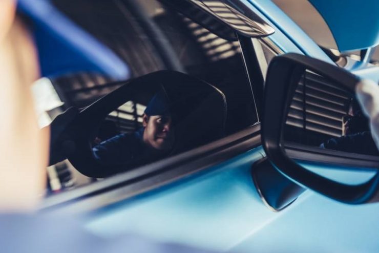 Un homme changeant un rétroviseur sur une voiture bleue