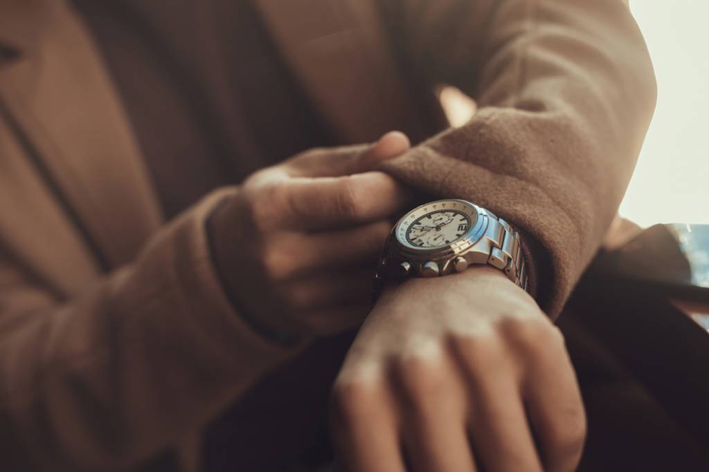 Man pulling the sleeve of his coat to read the time on his watch