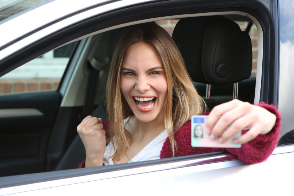 femme au volant montrant son permis de conduire